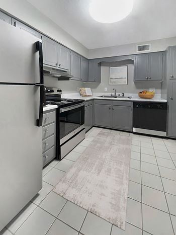 a kitchen with gray cabinets and black appliances and a white tile floor